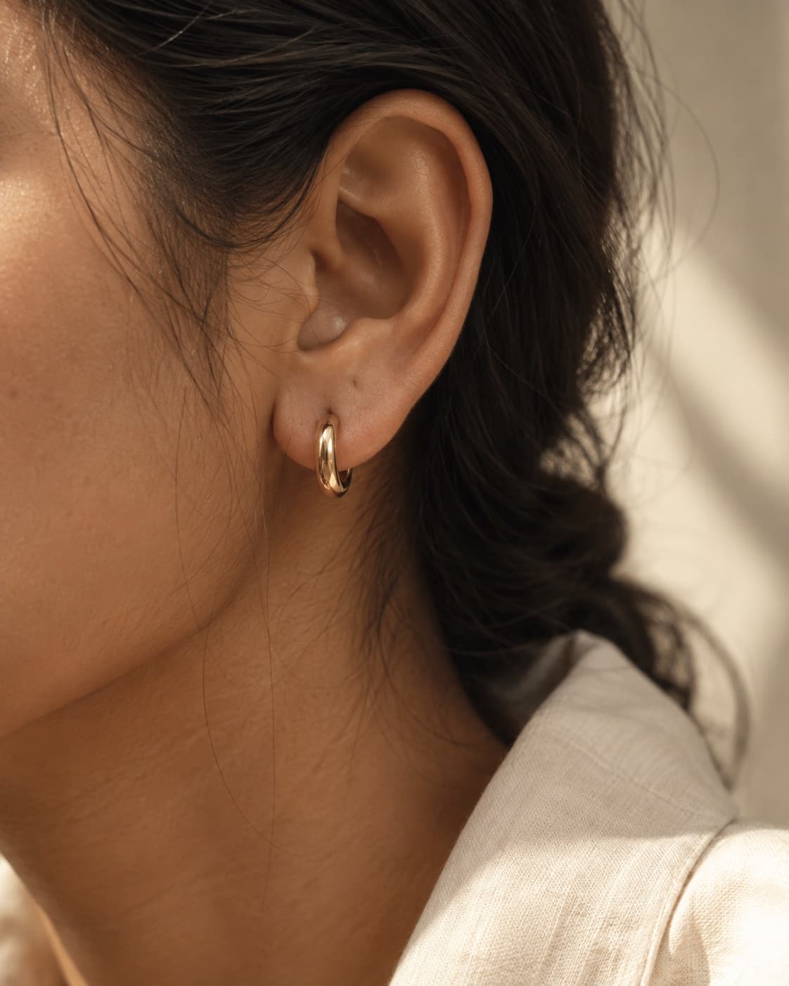 Concept photograph of a small gold-tone hoop worn in daylight